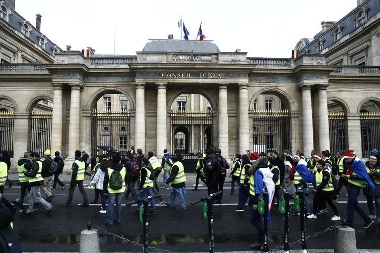 Des gilets jaunes passent devant le Conseil d'État à Paris.